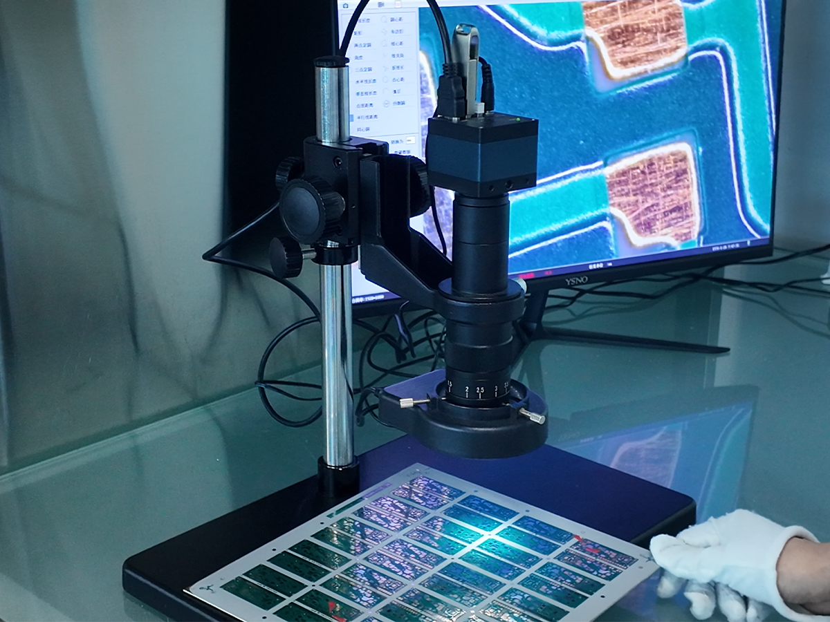 Microscope inspection of a PCB panel with magnified circuit details displayed on a monitor.
